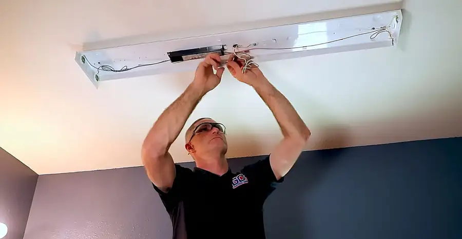 Justin working inside an opened LED strip fixture on a ceiling